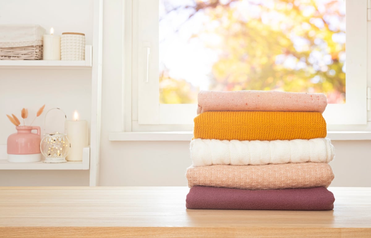 Neat stacks of freshly folded colorful clothes on a wooden table